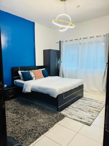 een slaapkamer met een bed met een blauwe muur bij Cozy Dala Room in Sharjah
