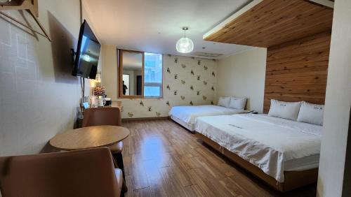 Gimhae Business Hotel K في Gimhae: غرفة نوم بسريرين وتلفزيون وطاولة