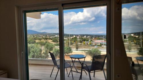 a balcony with chairs and a table in front of a window at AIR-IN Rooms with magnificent views- Airport shuttle in Artemida