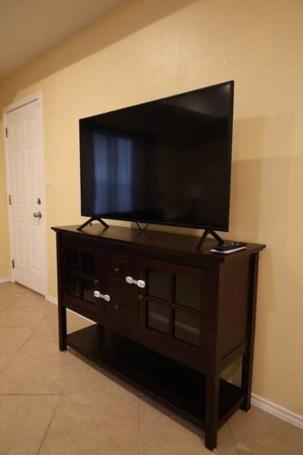a flat screen tv on a stand in a room at Mirror, mirror on the wall! in McAllen