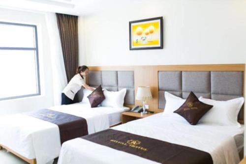 岑山的住宿－Royal Hotel Sầm Sơn，站在酒店房间两张床之间的女人