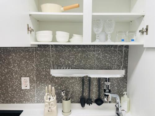 a kitchen counter with white cabinets and plates and glasses at SurfResort INN-The City YangYang in Yangyang