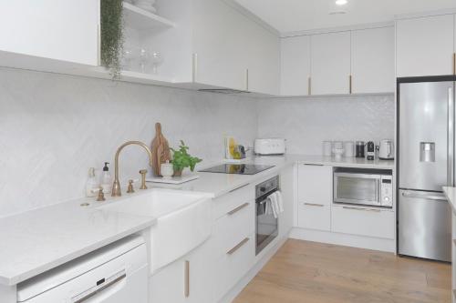 a white kitchen with a sink and a refrigerator at Carterley House in Christchurch