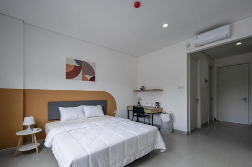 a bedroom with a large white bed and a table at Cove Nawaprita in Jakarta