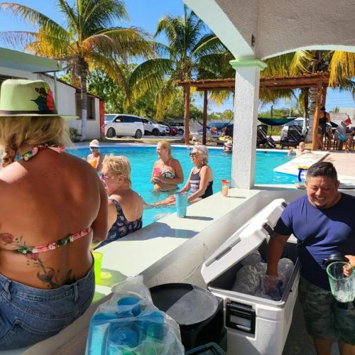 a group of people sitting around a swimming pool at Pelican Inn at Las Dunas Chelem in Chelem