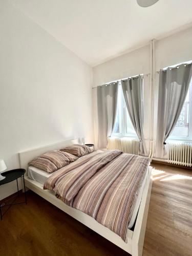 a white bedroom with a bed and two windows at Suite One Langestr II in Varel