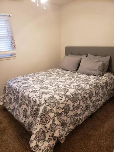 a bed with a black and white comforter in a bedroom at Centrally located to Strip, UNLV, Stadiums and so much more! in Las Vegas