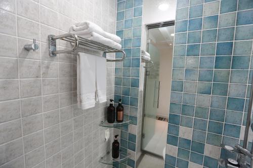 a bathroom with a shower with blue tiles at Hamdeok Beach Stay Jeju in Jeju