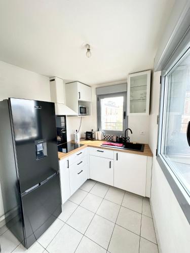 une cuisine avec des armoires blanches et un réfrigérateur noir dans l'établissement Magnificent apart Paris Bagnolet 401 with view, à Bagnolet