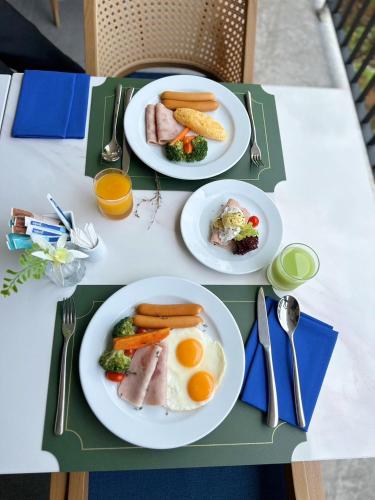 a table with two plates of breakfast food on it at The Proud Karon Beach Phuket Trademark Collection By Wyndham in Karon Beach