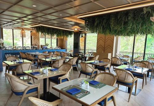 a restaurant with tables and chairs and a bar at The Proud Karon Beach Phuket Trademark Collection By Wyndham in Karon Beach