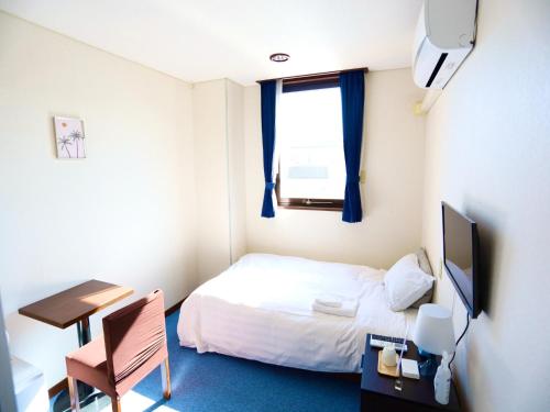 a small room with a bed and a desk and a television at Hotel Nomad - Vacation STAY 73941v in Hitachi