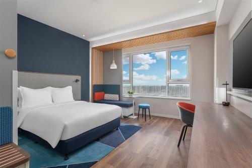 銀川市にあるHoliday Inn Express Yinchuan Downtown, an IHG Hotelのベッドとデスクが備わるホテルルームです。