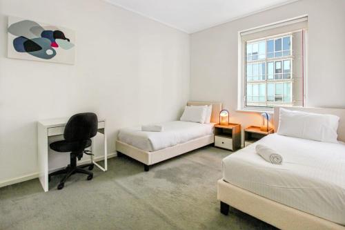 a bedroom with two beds and a desk and a chair at 3 BR 2 Bath 2 Carparks next to Crown Casino in Melbourne