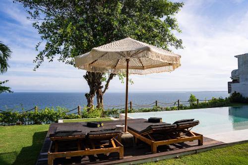 an umbrella and chairs next to a swimming pool at Villa Selatan in Jimbaran