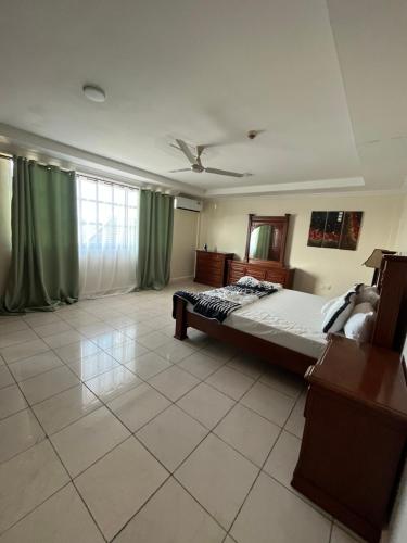 een slaapkamer met een groot bed en groene gordijnen bij FINE HOMES MIKOCHENI in Dar es Salaam