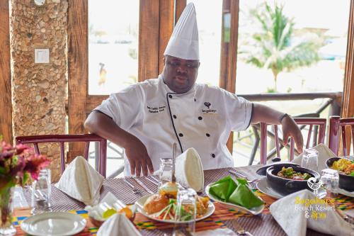 a chef standing in front of a table with food at Sogakope Beach Resort & Spa in Sogakofe