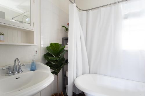a bathroom with a sink and a white shower curtain at Stylish 2bed 2bath Culver Cottage with bicycles in Los Angeles