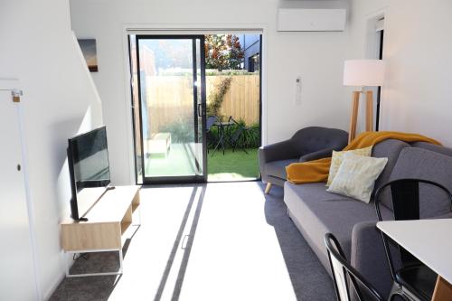 a living room with a couch and a television at Modern CBD, Walk to Te Pae, Across from Casino, FREE Parking in Christchurch