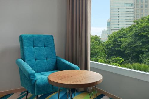 a blue chair and a table in a room with a window at Holiday Inn Express Jakarta Wahid Hasyim by IHG in Jakarta
