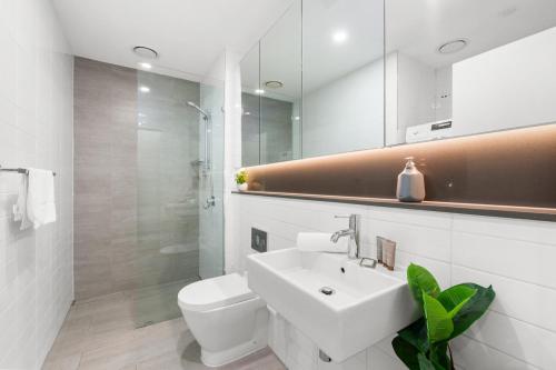 a white bathroom with a sink and a toilet at 1-Bed Unit with Alfresco Dining and BBQ in Sydney