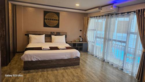 a bedroom with a bed and a large window at Central Guesthouse Chiang Rai - Bread & Breakfast in Chiang Rai