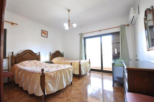a bedroom with two beds and a large window at Private pool villa walking distance to the centre in Loulé