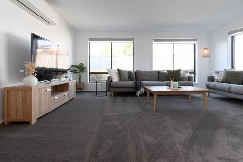 a living room with a couch and a tv at 3 Bedroom Home: Parking & WiFi in Kings Meadows