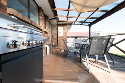 an outdoor patio with a grill and a table and chairs at 3 Bedroom Home: Parking & WiFi in Kings Meadows