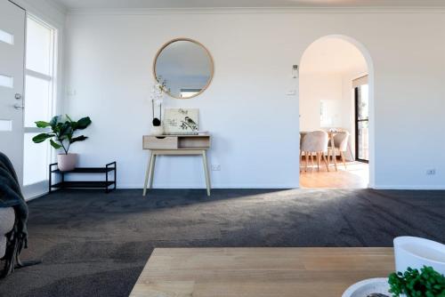 a living room with a mirror and a table at 3 Bedroom Home: Parking & WiFi in Kings Meadows