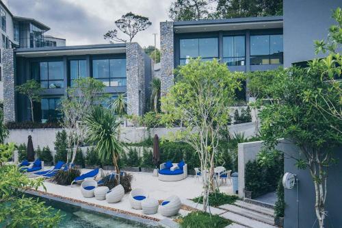 a building with a courtyard with blue chairs and trees at 2BR Pavilion near Kamala Beach, Natural Park P10 in Kamala Beach