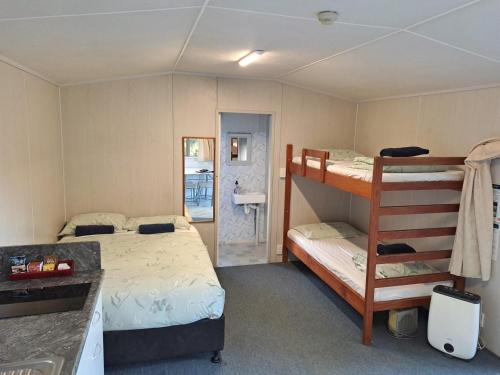 a bedroom with two bunk beds and a bathroom at Whatuwhiwhi TOP 10 Holiday Park in Tokerau Beach