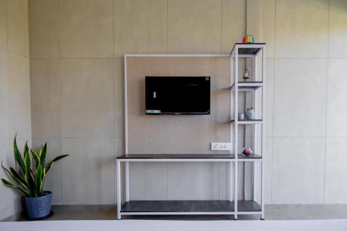 a living room with a tv on a wall at Stayscape Abalone 6BHK Alibaug in Kīhīm