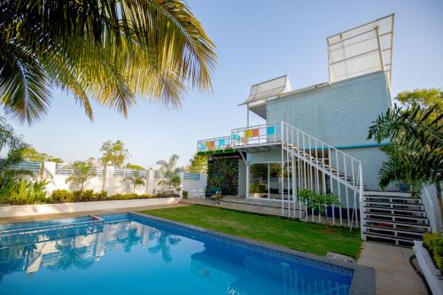 a house with a swimming pool in front of it at Stayscape Abalone 6BHK Alibaug in Kīhīm