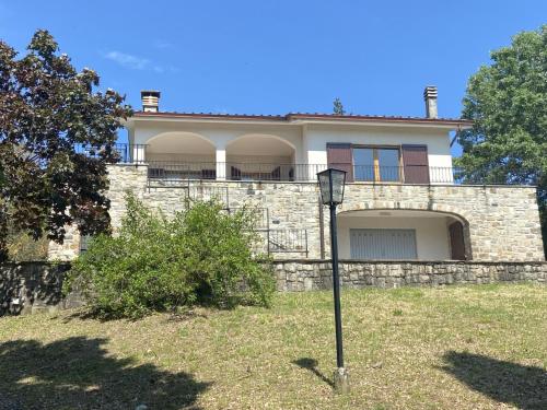 La Casa del Bosco - Villa con vista panoramica su Bobbio e la Val Trebbia في بوبيو: منزل كبير بجدار حجري واضاءة الشارع