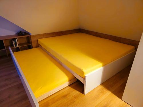 2 camas en una habitación pequeña con sábanas amarillas en Apartmán PANORÁMA en Liptovský Mikuláš