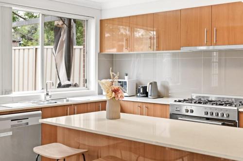 a kitchen with wooden cabinets and a white counter top at Cozy Double Room in Panania - Close to Stations & Stores - Shared Bathroom in Panania