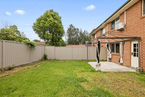 a fence in a yard next to a house at Cozy Double Room in Panania - Close to Stations & Stores - Shared Bathroom in Panania