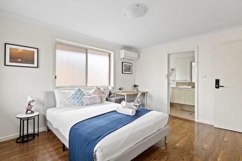 a bedroom with a large bed with a blue blanket at Luxe Ensuite Queen Room in Panania - Nearby Station in Panania