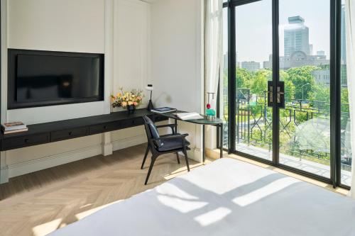 a bedroom with a tv and a desk with a chair at Opartment - People's Square 远东饭店 - 人民广场 in Shanghai