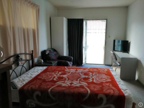 Habitación de hotel con cama roja y sala de estar. en 驿站, en Auckland