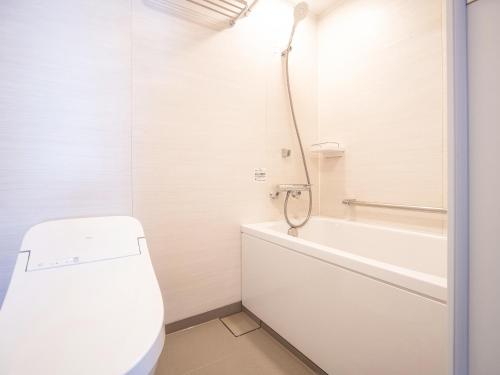 a white bathroom with a tub and a toilet at Vessel Hotel Kurashiki in Kurashiki