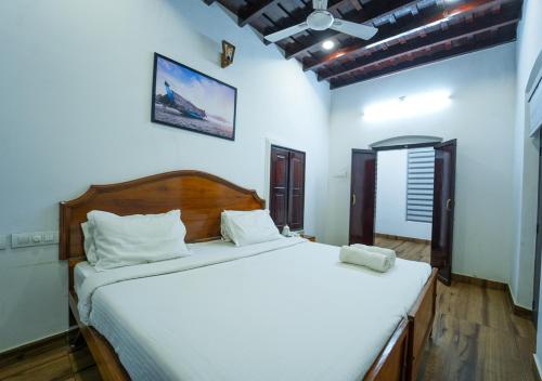 a bedroom with a large bed with white sheets at Pop Tavern Kovalam Beach Villa by VOYE HOMES in Kovalam