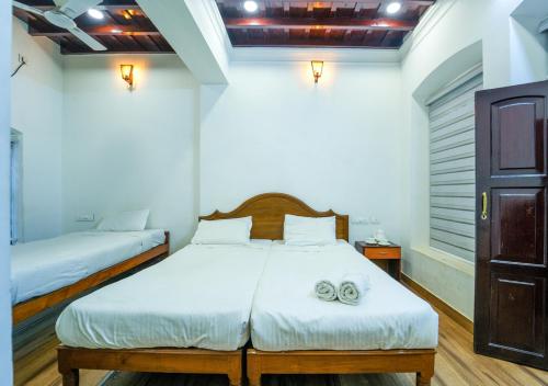 a bedroom with two beds with towels on it at Pop Tavern Kovalam Beach Villa by VOYE HOMES in Kovalam