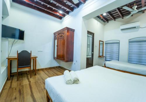 a bedroom with a bed and a desk and a tv at Pop Tavern Kovalam Beach Villa by VOYE HOMES in Kovalam
