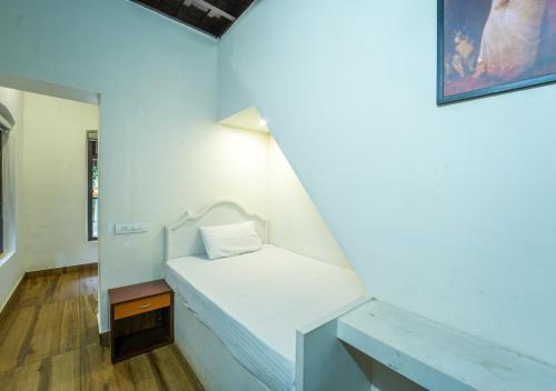 a small bed in a room with a mirror at Pop Tavern Kovalam Beach Villa by VOYE HOMES in Kovalam
