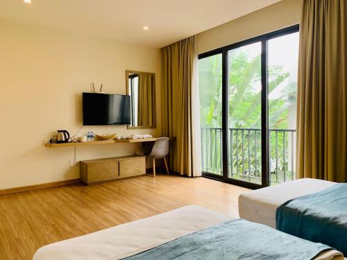 a hotel room with two beds and a television at Vila Lotus Hạ Long in Ha Long