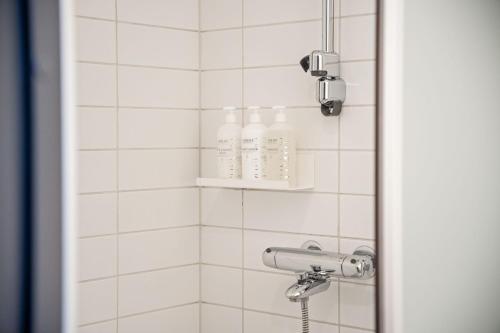 a bathroom with a shower with white tiled walls at Original Sokos Hotel Vaakuna Mikkeli in Mikkeli