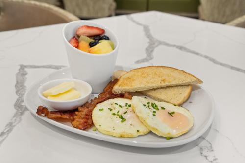 a plate of food with eggs toast and a bowl of fruit at EVEN Hotel Austin Uptown near the Domain by IHG in Austin