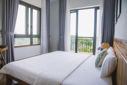 a bedroom with a bed with a large window at SEN VILLA Boutique in Bao Loc